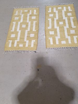 pair of yellow and white rugs sitting on top of a white floor