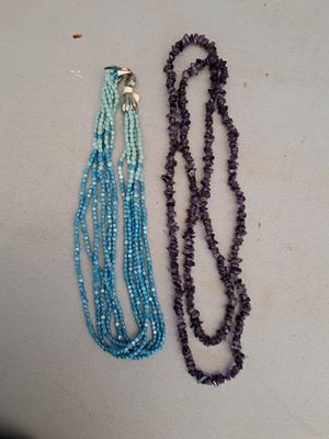 deux colliers de couleurs et de tailles différentes posés sur une surface blanche