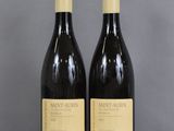 two bottles of wine sitting on top of a table next to each other