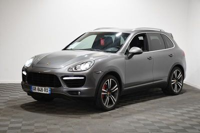 Une Porsche Cayenne grise est garée sur un sol à damier
