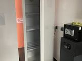 an open refrigerator in the corner of a room next to a trash can