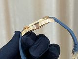 a person wearing gloves holding a gold and blue watch