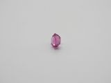 a single pink sapphire stone on a white surface