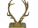des bois de cerf en laiton posés sur un socle carré, sur fond blanc