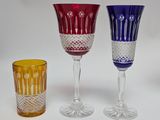 three different colored wine glasses sitting next to each other on a white surface