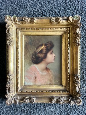 an old picture of a woman in a pink dress in a gold frame on a blue carpet