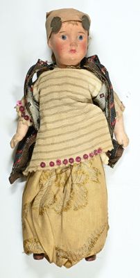an old doll with a brown outfit and a hat on a white surface