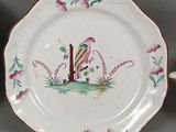 a plate with a bird painted on it next to a cup and saucer
