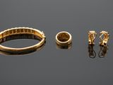 two gold rings and a pair of earrings on a reflective surface