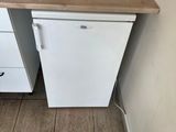 a small white refrigerator in a small kitchen