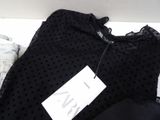 the top of a black top with polka dots on it is next to a pair of jeans