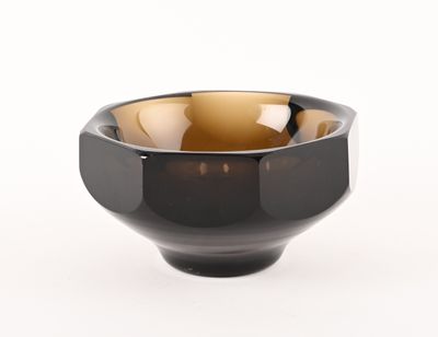 un bol noir et marron posé sur une surface blanche, avec un fond blanc