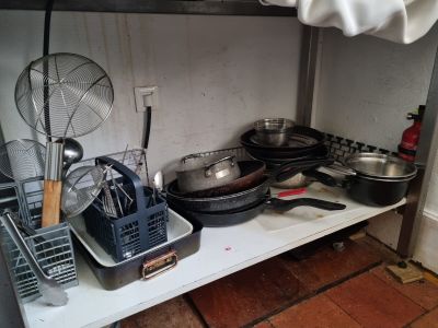 de nombreuses casseroles et poêles sur une étagère dans la cuisine