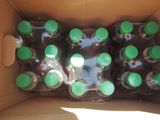 six bottles of soda in a cardboard box with green caps