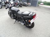 a black motorcycle parked in a parking lot with other motorcycles in the background
