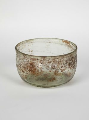 an old glass bowl with a rusted surface on a white surface