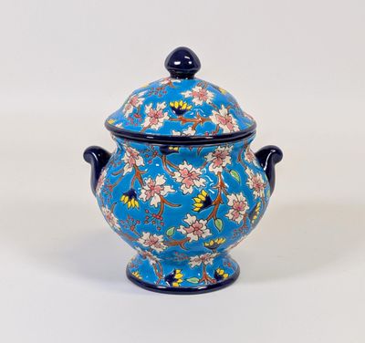 un vase bleu orné de fleurs, posé sur une surface blanche