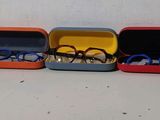 cinq paires de lunettes dans un étui posé sur une table