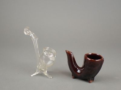 une pipe en verre et un vase en verre posés l'un à côté de l'autre
