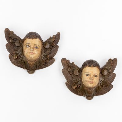 pair of carved wood angel heads on a white background