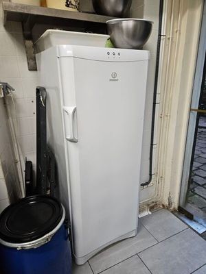 un réfrigérateur blanc et une poubelle bleue dans une cuisine