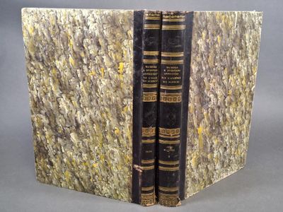 un vieux livre sur lequel sont posés deux autres livres, posé sur une table