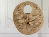 sac en paille tressée accroché à un mur