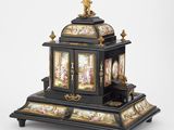 une horloge noire et dorée surmontée d'une statue