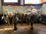 deux vases posés par terre, dans lesquels se trouvent des fleurs