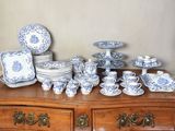 une commode sur laquelle sont disposées de nombreuses pièces de vaisselle bleue et blanche