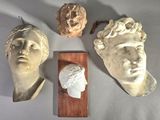trois têtes de statues sont exposées sur une table, accompagnées d'une plaque en bois