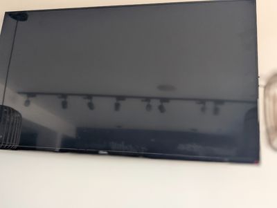 une télévision à écran plat accrochée au mur au-dessus d'une lampe