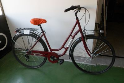 un vélo rouge garé dans une pièce au sol vert