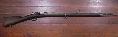 an old rifle is laying on a wooden floor next to a wall
