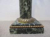 un vase vert et doré posé sur un socle en marbre
