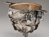an antique silver cup with a spoon in the middle of it