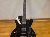 a black electric guitar sitting on a hard wood floor