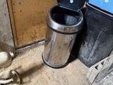 une poubelle posée à côté d'une autre poubelle, par terre