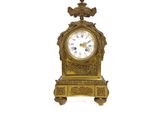 une horloge en or surmontée d'un oiseau