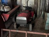 a red lawn mower in a barn with other tools