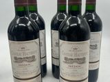 six bottles of wine are lined up on a white surface