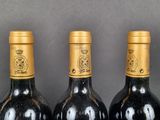 three bottles of wine are lined up on a shelf