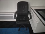 a black office chair sitting in front of a computer desk