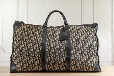 un sac de voyage marron et noir posé sur un parquet