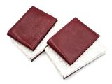 two leather wallets sitting on top of each other on a white surface
