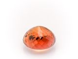 a close up of a faceted orange sapphire stone on a white surface