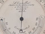 a close up of a clock with a barometer on it