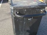 a black suitcase sitting in a parking lot next to a forklift