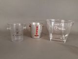 trois verres à shot et un verre doseur sont posés sur une table