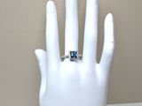 a hand with a ring on it that has a blue stone in it
